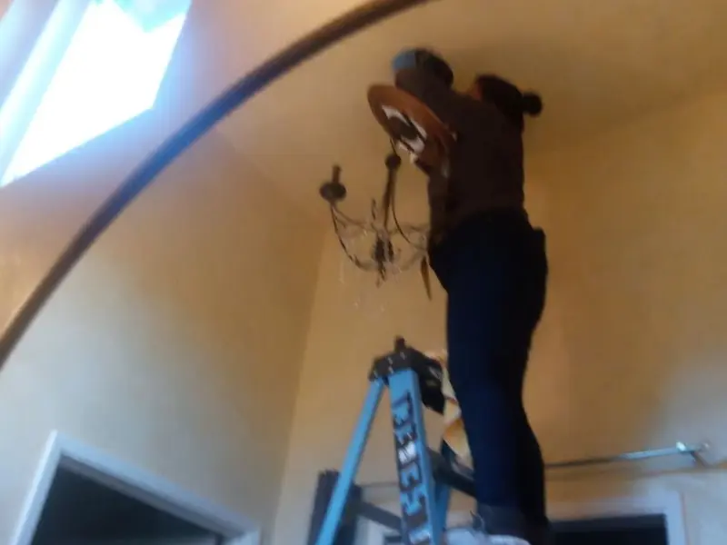 Electrician installing a chandelier in a Delta residence